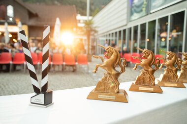 Die Trophäen, das Goldene Einhorn, stehen auf einem Tisch vor den Zuschauerreihen beim Alpinale Kurzfilmfestival bereit. | © Anna Salcher