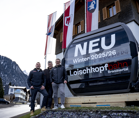 Die neue 10er Gondel der Loischkopfbahn steht vor dem Gemeindezentrum Bürserberg. Die Bürgermeister der Dörfer Brand und Bürserberg und der Geschäftsführer der Bergbahnen Brandnertal stehen vor der Gondel. | © Bergbahnen Brandnertal, Viviane Seils
